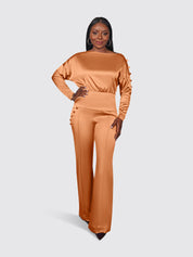 Woman wearing a satin jumpsuit on a plain background